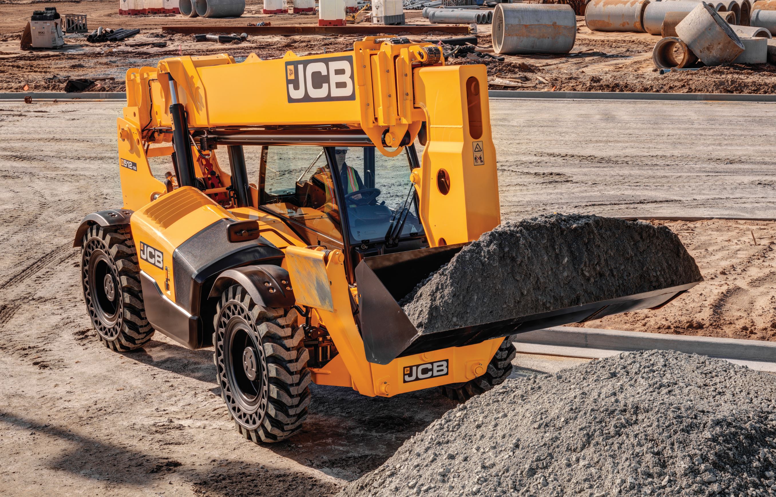Yellow JCB 512-56 telehandler with a bucket at a worksite
