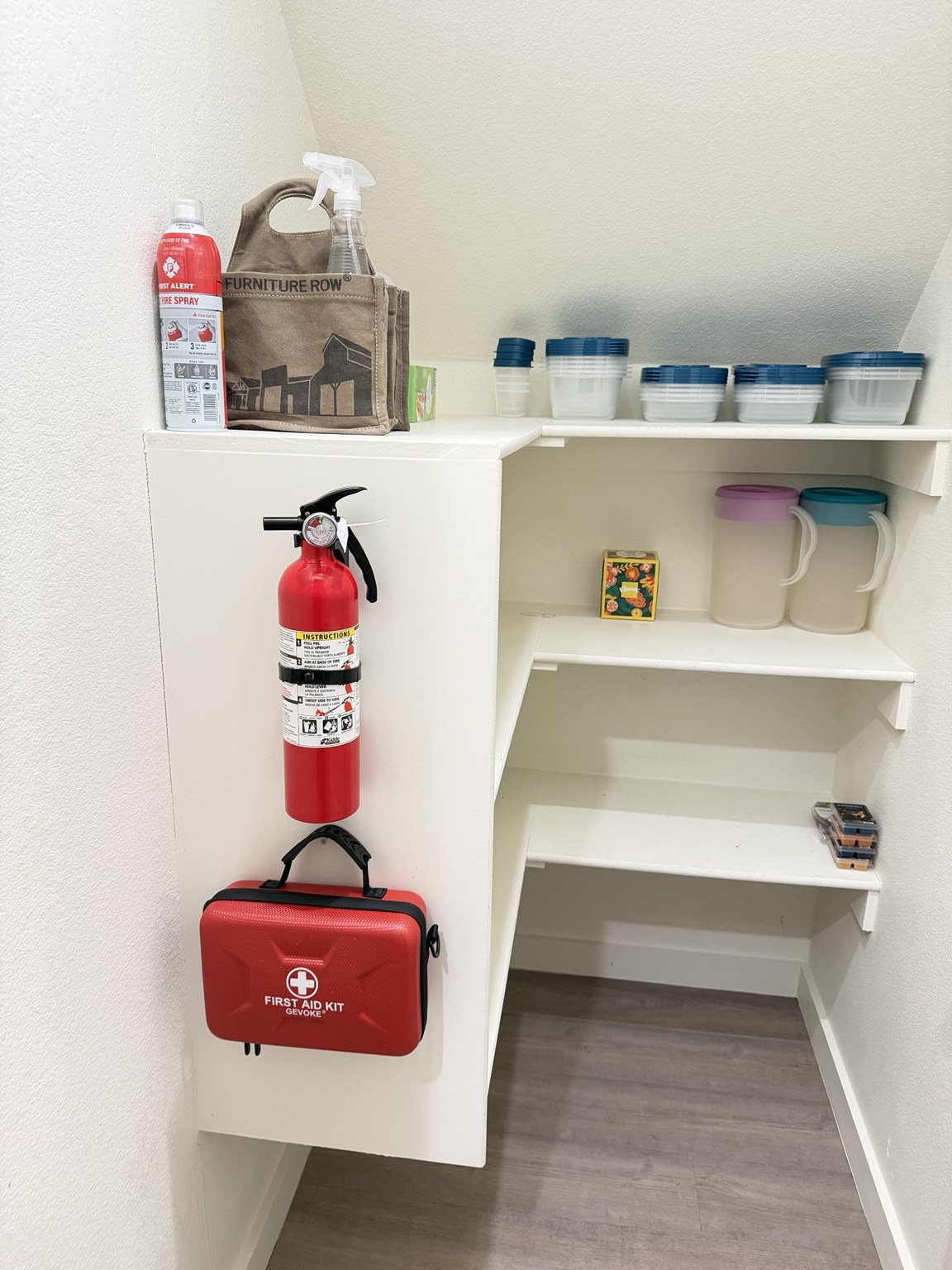 Fire extinguisher and red first-aid kit mounted on the left side of the pantry